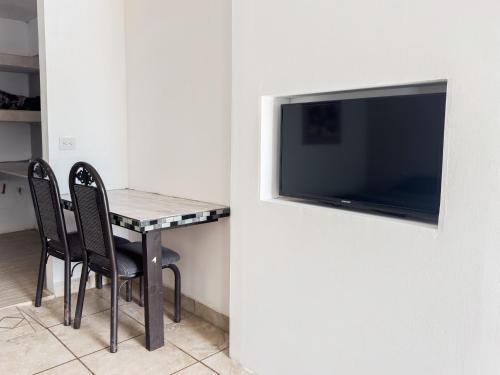 a table with chairs and a television on a wall at Eco Bay Hotel in Bahía Kino