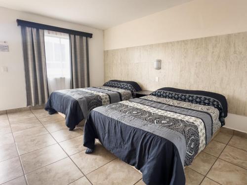 three beds in a room with a window at Eco Bay Hotel in Bahía Kino