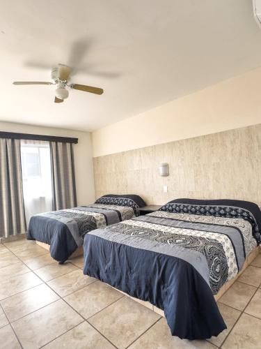 two beds in a room with a ceiling fan at Eco Bay Hotel in Bahía Kino