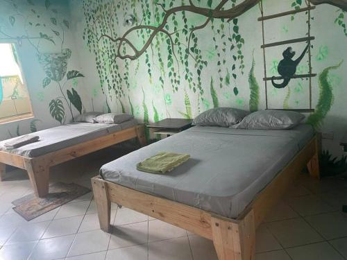 Un dormitorio con 2 camas y una pared con plantas. en Cahuita Vibe en Cahuita