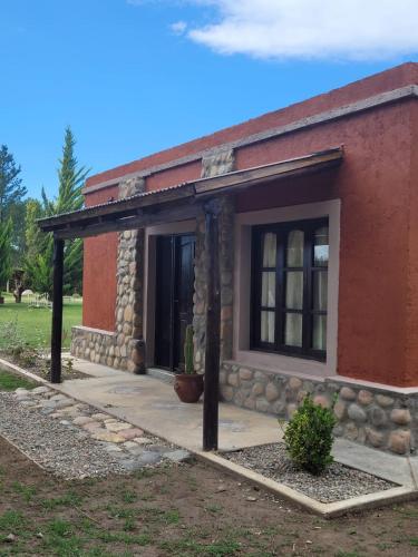 uma pequena casa vermelha com uma parede de pedra e um alpendre em Casa de Campo Don Valentin em Tunuyán