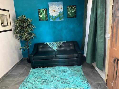 a black leather couch in a blue room with a rug at Departamento Tulipán in San Felipe