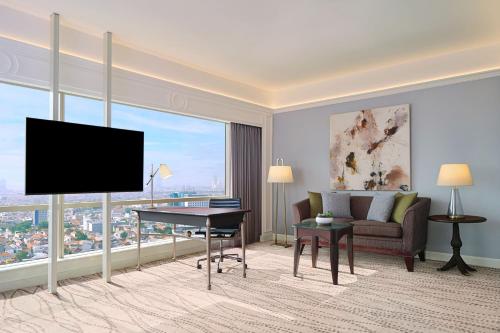 a living room with a television and a couch at JW Marriott Hotel Surabaya in Surabaya
