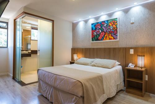 a bedroom with a large bed and a shower at Hotel Serra Everest in Nova Friburgo