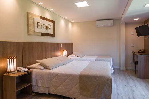 a hotel room with two beds and a television at Hotel Serra Everest in Nova Friburgo
