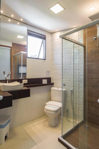 a bathroom with a toilet and a glass shower at Hotel Serra Everest in Nova Friburgo