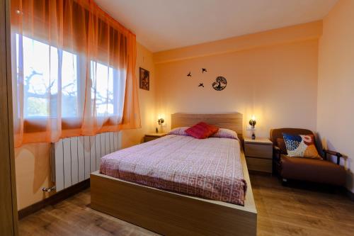 a bedroom with a bed and a chair and a window at Masia Cal Tonarro in San Martín Sarroca