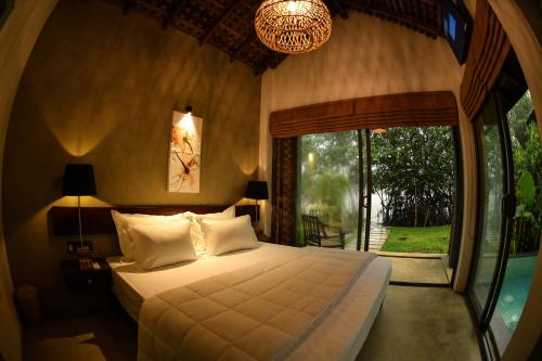 a bedroom with a bed and a large window at Pivithuru River Cabanas in Hikkaduwa