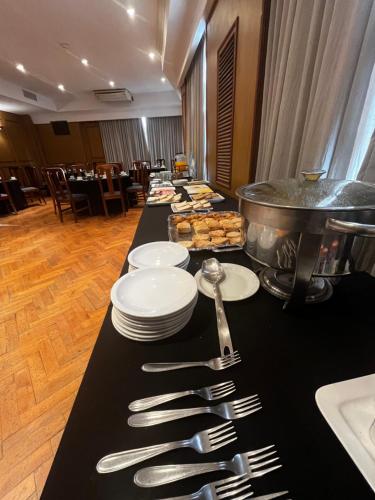 a long black table with plates and silver utensils at Hotel Catalinas Tucuman in San Miguel de Tucumán