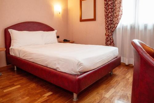 a bed with a red headboard in a room at SIRIOHotel in Dormelletto