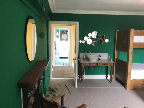 a bathroom with a sink and a bedroom with green walls at Mansefield Rooms in Lockerbie