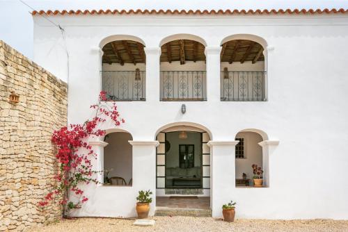 - un bâtiment blanc avec des fenêtres cintrées et des fleurs dans l'établissement CAN FERRER Authentic payesa house, à Sant Antoni de Portmany
