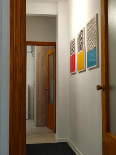 a hallway with paintings on the wall and a door at Apartamentos Rincón del Roldán - La Rinconada in San Jose de la Rinconada