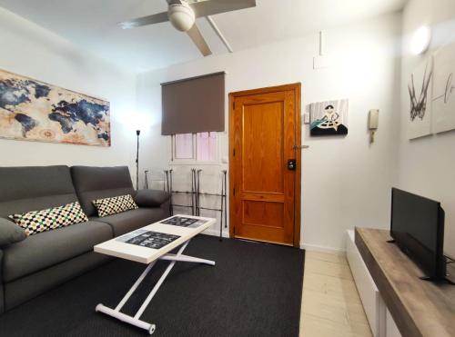 a living room with a couch and a television at Apartamentos Rincón del Roldán - La Rinconada in San Jose de la Rinconada