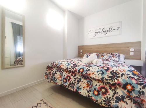 a bedroom with a bed with a floral bedspread at Apartamentos Rincón del Roldán - La Rinconada in San Jose de la Rinconada