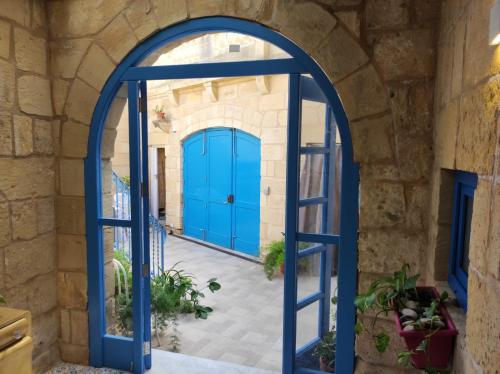 an archway with blue doors in a stone building at Il Hnejja Farmhouse in Mqabba