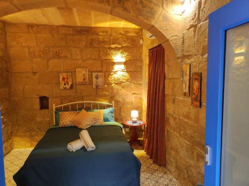 a bedroom with a bed in a stone wall at Il Hnejja Farmhouse in Mqabba