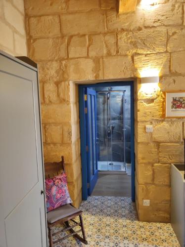 a hallway with a blue door and a chair at Il Hnejja Farmhouse in Mqabba