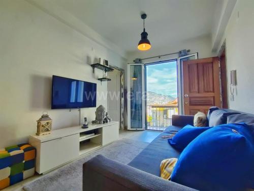 ein Wohnzimmer mit einem blauen Sofa und einem TV in der Unterkunft Lydia's Place in Funchal