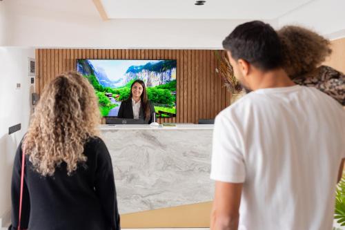 un grupo de personas viendo a una mujer en la televisión en Appart Hôtel Rambla en Marrakech