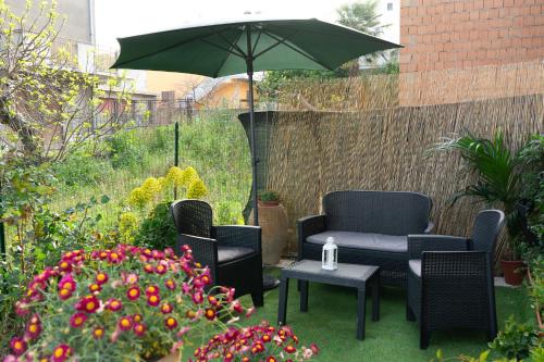 un patio con sillas, sombrilla y flores en Casa di Nonna Linda, en Portocannone