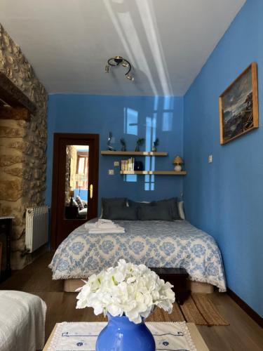 Un dormitorio azul con una cama y un jarrón con flores en La Venta de Izan, en Gumiel de Hizán