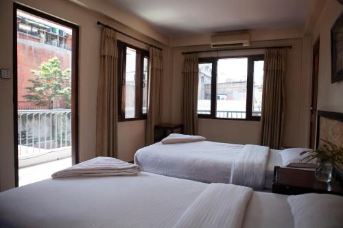 two beds in a room with two windows at Hotel Northfield in Kathmandu