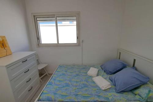 une chambre avec un lit avec des oreillers bleus et une fenêtre dans l'établissement Palavas, à Palavas-les-Flots