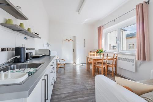 a kitchen with white cabinets and a dining room with a table at Apartmány Rozárka Turnov in Turnov
