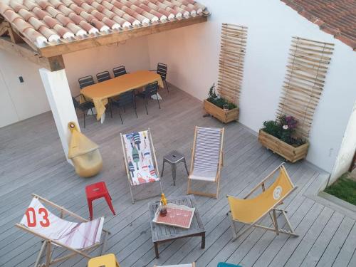 un patio avec une table et des chaises sur une terrasse dans l'établissement Maison familiale en version 10 pers. plage à 300 m, à LʼÉpine