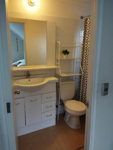 een badkamer met een wastafel, een toilet en een spiegel bij Casa 3 dormitorios 3 baños Osorno in Osorno