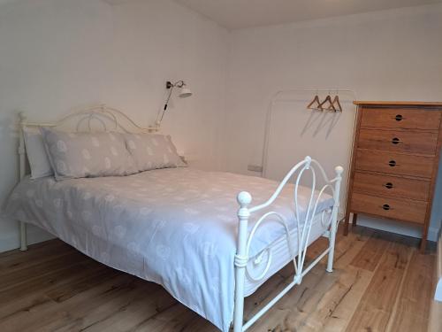 1 dormitorio con cama blanca y vestidor en Darrell Cottage, en Kanturk