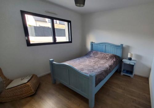 une chambre avec un lit bleu et une fenêtre dans l'établissement Maison proche du centre, à Auray