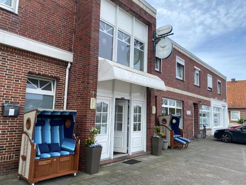 a store front with blue chairs outside of a brick building at STRANDNEST NORDDEICH in Norddeich