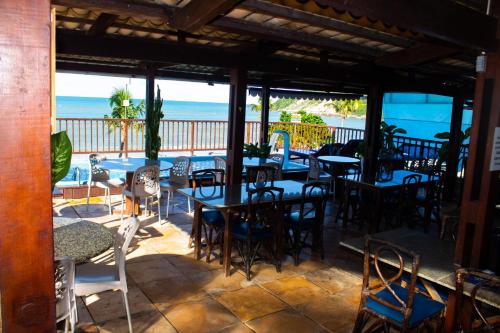 a patio with tables and chairs and the ocean at Hotel Pousada Azzurra in Natal