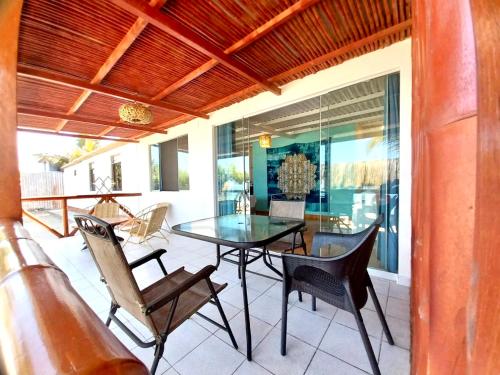a patio with a glass table and chairs at Casuarinas del Mar Habitacion Playa in Canoas De Punta Sal