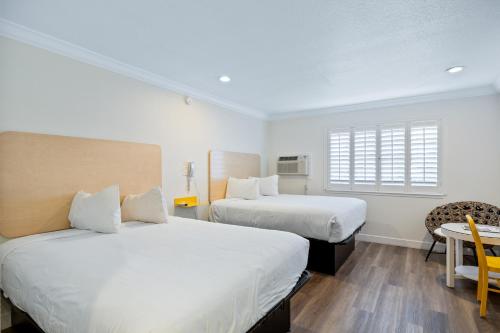 1 dormitorio con 2 camas, mesa y ventana en Gateway Lodge, en Seaside