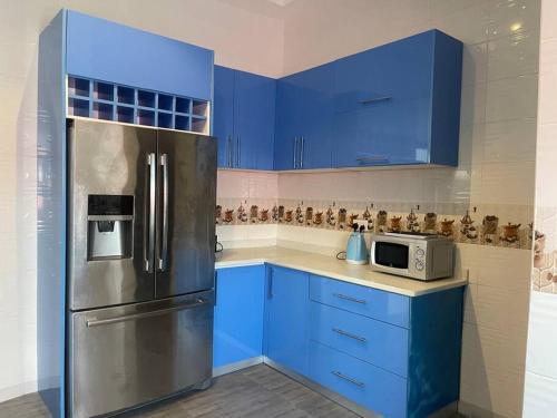 een keuken met blauwe kasten en een roestvrijstalen koelkast bij Amazing Grace Apartment in Cape Coast