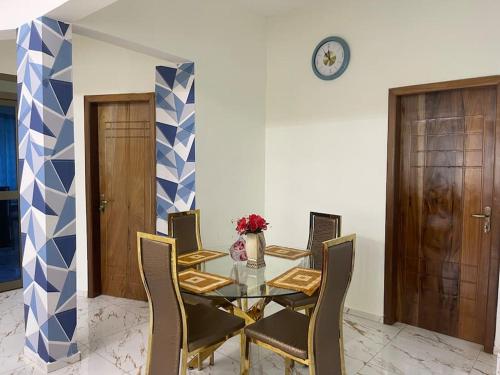 uma sala de jantar com mesa e cadeiras e um relógio em Amazing Grace Apartment em Cape Coast