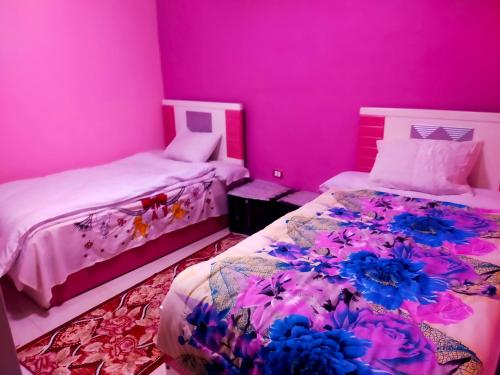 2 camas en una habitación con paredes rosas en Migo Pyramids View, en El Cairo
