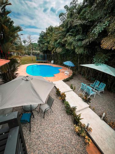 un patio con sombrilla, sillas y piscina en Casa hotel Aeroclubr15, en Villavicencio
