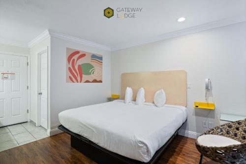 a bedroom with a large white bed and a chair at Gateway Lodge in Seaside