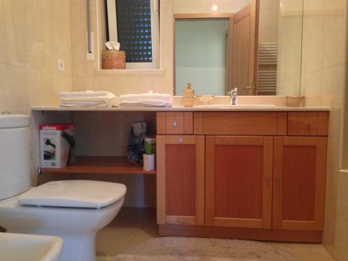 a bathroom with a sink and a toilet and a mirror at Atlantic Ocean & Pool Apartment in Figueira da Foz