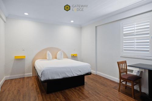 a bedroom with a bed with white sheets and a desk at Gateway Lodge in Seaside