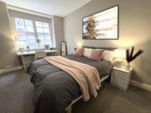 a bedroom with a bed and a desk and two windows at 2BD Kings Cross & St Pancras Elegance in London