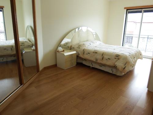 a small bedroom with a bed and a mirror at Atlantic Ocean & Pool Apartment in Figueira da Foz