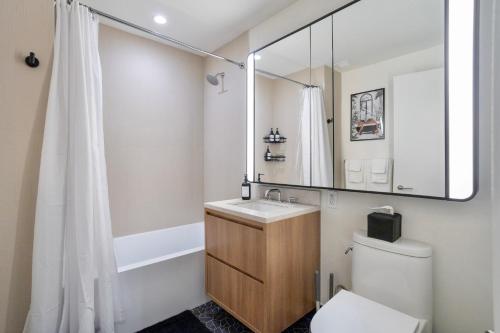 W łazience znajduje się umywalka, toaleta i lustro. w obiekcie Prime NYC Waterfront Gem w mieście Mott Haven
