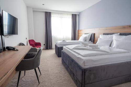 a hotel room with two beds and a desk at Hotel Sistems in Banja Luka