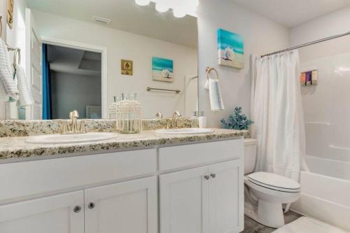a white bathroom with two sinks and a toilet at Retreat at the Oasis in Pensacola