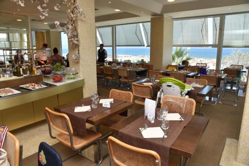 a restaurant with wooden tables and chairs and windows at Hotel Fedora Riccione in Riccione